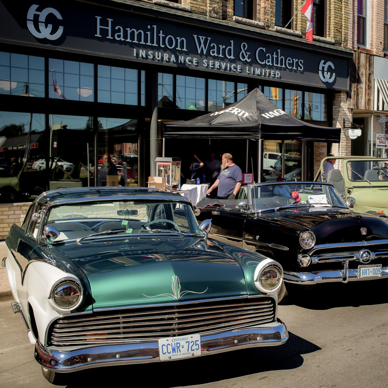 There are two old-fashion cars in front of Hamilton Ward & Cathers on Talbot St.